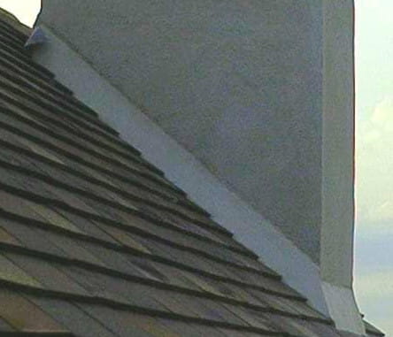 Travaux de couvreur réalisant un solin de mortier sur crépis de cheminée